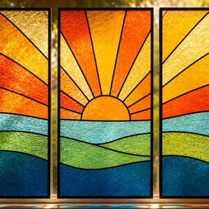 Puede incluir: Un panel de vidriera en tríptico que muestra un amanecer sobre un paisaje. El diseño incluye un sol amarillo con rayos naranjas y rojos sobre bandas horizontales de vidrio azul claro, verde y azul oscuro, todo enmarcado en color negro.