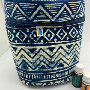 Peut inclure: Une trousse de transport en tissu bleu et blanc à motifs avec une fermeture à glissière. La trousse est conçue pour contenir des flacons d'huiles essentielles. Deux flacons d'huiles essentielles sont visibles sur l'image.