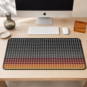 Puede incluir: Una alfombrilla de escritorio rectangular con un patrón de cuadrícula de líneas blancas finas sobre un fondo degradado que transita de negro en la parte superior a gris oscuro, rojo intenso, naranja quemado y un tono bronceado claro.