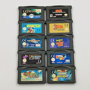 Może przedstawiać: Kolekcja dziesięciu czarnych kartridży do gry Game Boy Advance ułożonych w dwie kolumny. Etykiety zawierają tytuły takie jak The Lord of the Rings, Tekken Advance, Lucky Luke Wanted, The Legend of Zelda, Medabots, Mario vs. Donkey Kong, F-Zero, Street Fighter Alpha 3, Super Mario Advance oraz Digimon Battle Spirit 2.