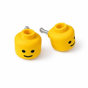 Könnte beinhalten: Zwei gelbe Manschettenknöpfe im Lego-Stil mit schwarzen Smiley-Gesichtern. Die Manschettenknöpfe haben silberne Stifte und sind vor einem weißen Hintergrund platziert. Ein lustiges Accessoire.