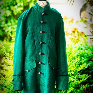 May include: A long-sleeved emerald green coat featuring a tonal damask pattern, a high mandarin collar, and a front closure with six decorative silver-toned metal buttons secured by black fabric loops. Two flap pockets are on the front.