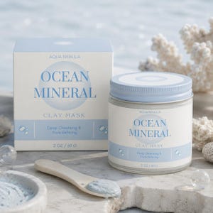 May include: A light blue and white box and a matching jar of Aqua Nebula Ocean Mineral Clay Mask. The labels feature the text Ocean Mineral, Clay Mask, Deep Cleansing & Pore Refining, and 2 oz / 60 g. A small wooden scoop with blue clay sits nearby.