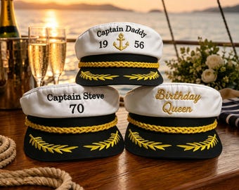 Könnte beinhalten: Drei weiß-schwarze Kapitänsmützen mit goldener Kordelverzierung und gestickten Lorbeerblättern auf dem Schirm. Die obere Mütze zeigt Captain Daddy 1956 mit einem Anker, die untere linke Captain Steve 70 und die untere rechte Birthday Queen.