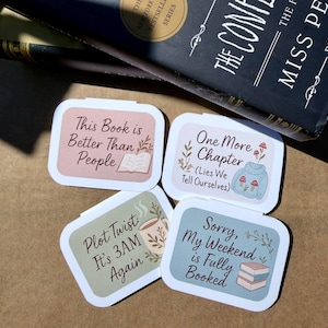 May include: Four rectangular stickers with rounded corners, each featuring a different book-related quote. The stickers have a white border and pastel backgrounds. One reads "This Book is Better Than People." Another says "One More Chapter." The others say "Plot Twist: It's 3AM Again" and "Sorry, My Weekend is Fully Booked."