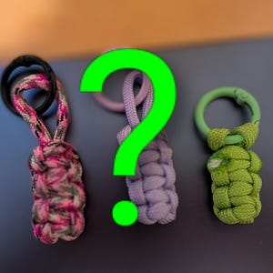 Może przedstawiać: Trzy ręcznie robione breloczki z paracordu w kolorze różowym, fioletowym i zielonym. Każdy breloczek ma pleciony wzór węzła i metalowy pierścień do mocowania kluczy. Różowy breloczek ma czarny pierścień, fioletowy ma fioletowy pierścień, a zielony ma zielony pierścień.