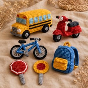 Puede incluir: Una colección de seis artículos de ganchillo que incluye un autobús escolar amarillo, un scooter rojo, una bicicleta azul, una mochila azul y amarilla, una señal de stop octogonal roja y una señal de tráfico circular amarilla.