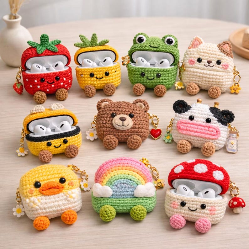 May include: A collection of ten crocheted cases for wireless earbuds, each featuring unique designs including a strawberry, pineapple, frog, cat, bear, cow, duck, rainbow, and mushroom, all with small attached charms and textured yarn details.