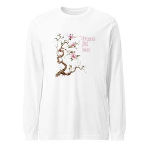 Può includere: Maglietta bianca a maniche lunghe con un'illustrazione ad acquerello di un albero in fiore con fiori rosa. Il testo "Flowers Dirt Trees" è stampato in rosa sul lato destro.