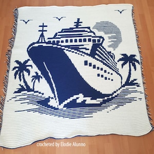 May include: A white and navy blue crocheted blanket featuring a cruise ship design. The blanket has a fringe border and depicts a ship, palm trees, birds, and a sun. The words "crocheted by Elodie Alunno" are at the bottom.