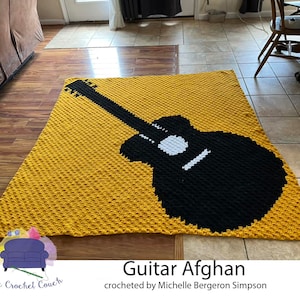 May include: A crocheted yellow blanket with a black silhouette of a guitar. The blanket is called "Guitar Afghan" and is crocheted by Michelle Bergeron Simpson.