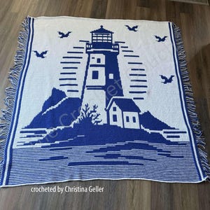 May include: A crocheted throw blanket featuring a blue and white lighthouse design. The blanket has a fringe border and the text "crocheted by Christina Geller" is at the bottom.