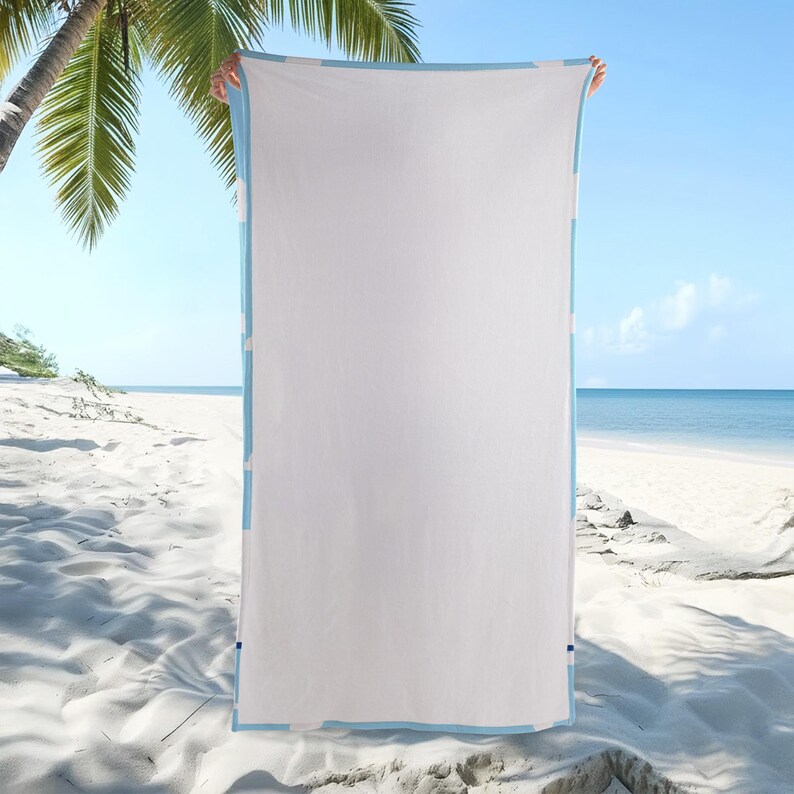 Puede incluir: Una toalla de playa rectangular que presenta un panel central grande de color blanco s&oacute;lido enmarcado por un borde azul claro. La toalla se sostiene verticalmente, mostrando su dise&ntilde;o limpio y minimalista y su textura suave en un entorno luminoso.