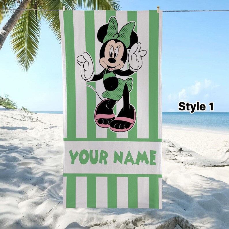 Pode incluir: Uma toalha de praia retangular com um padr&atilde;o de riscas verticais verdes e brancas. Centrado est&aacute; um gr&aacute;fico da Minnie Mouse com um la&ccedil;o, top e saia de bolinhas verdes e sand&aacute;lias cor-de-rosa. O texto YOUR NAME est&aacute; impresso em letras verdes.