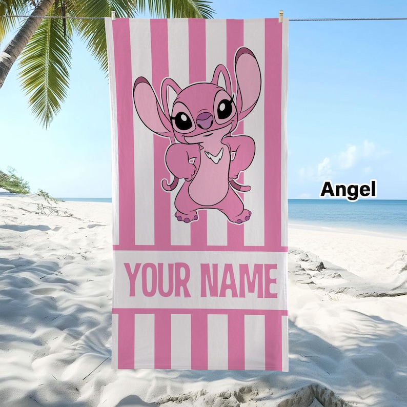 May include: A rectangular beach towel featuring a pink and white vertical striped pattern. The center displays a cartoon character named Angel with large ears and a pink body. Below the character is a white horizontal band with the text YOUR NAME.