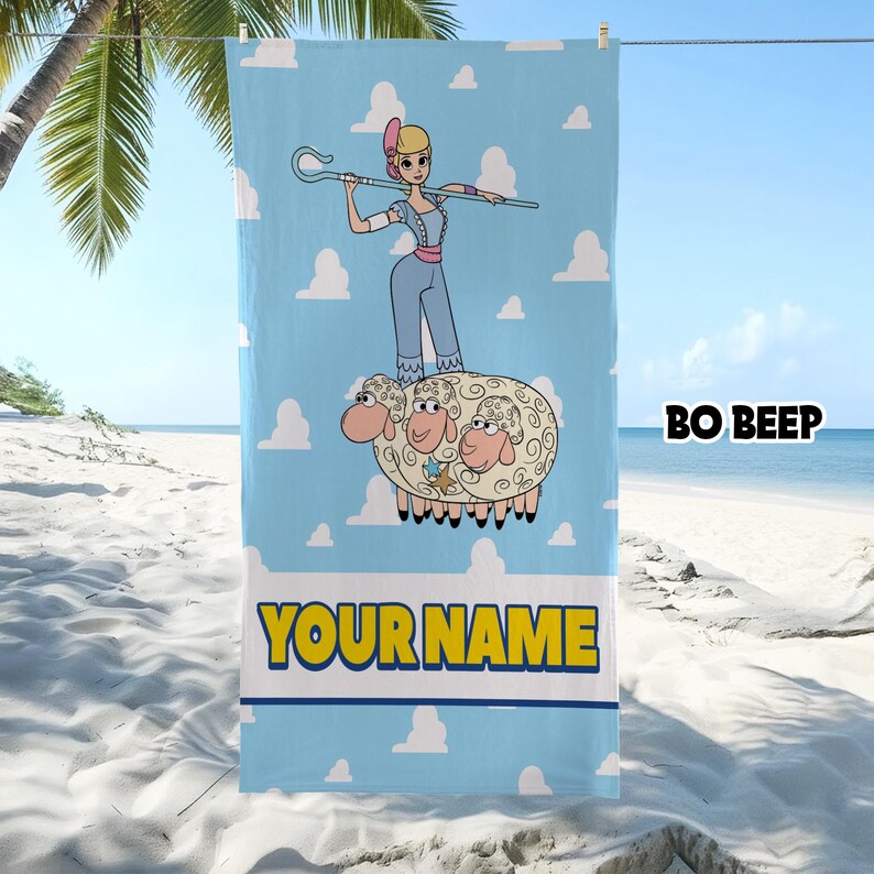 Puede incluir: Una toalla de playa rectangular de color azul claro con una ilustraci&oacute;n de dibujos animados de Bo Peep sosteniendo un cayado de pastor mientras est&aacute; de pie sobre tres ovejas. El fondo tiene nubes blancas. El texto BO BEEP y YOUR NAME est&aacute; impreso.