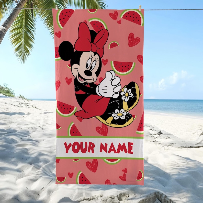 Pu&ograve; includere: Un telo mare rettangolare con sfondo rosa caratterizzato da un motivo di fette di anguria e cuori rossi. Minnie Mouse &egrave; al centro, indossa un fiocco rosso e sandali con fiori bianchi. Il testo YOUR NAME &egrave; stampato in colore rosso.