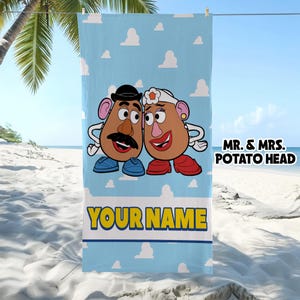 Op de afbeelding: Een rechthoekige strandhanddoek met een lichtblauwe achtergrond en witte wolken. Het ontwerp bevat de figuren Mr. en Mrs. Potato Head, de tekst MR. & MRS. POTATO HEAD en een gele banner met de tekst YOUR NAME.