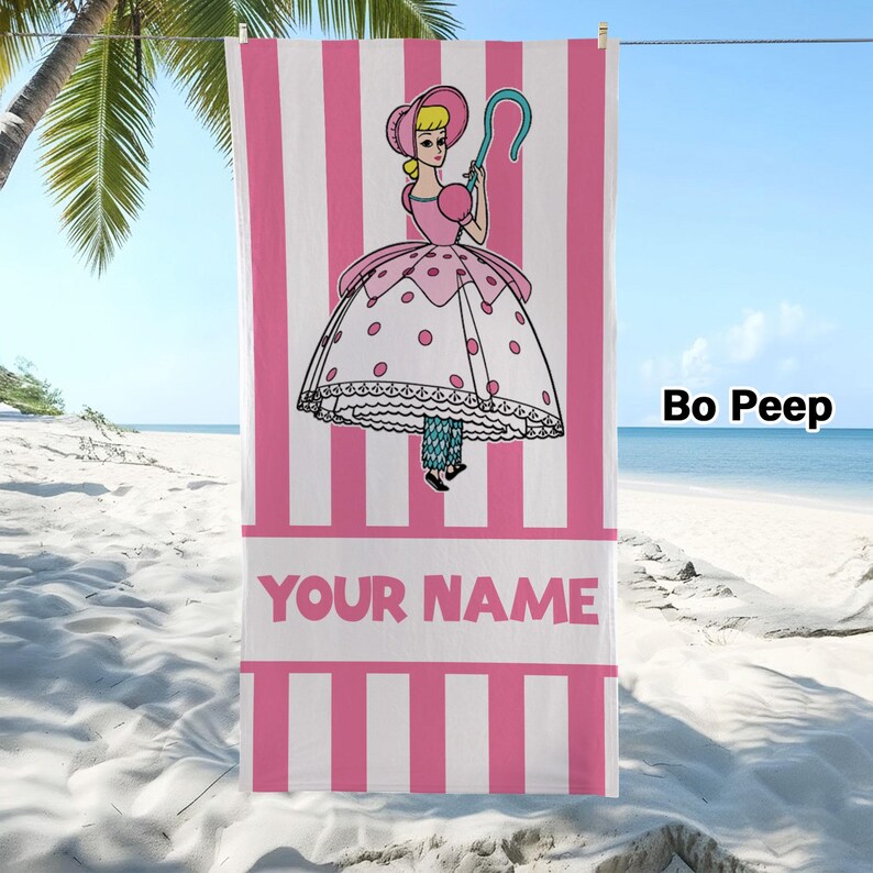 May include: A rectangular beach towel featuring a pink and white vertical striped pattern. The centre displays a cartoon illustration of a character wearing a bonnet and a polka-dot dress, holding a blue shepherd's crook. The text YOUR NAME is printed.