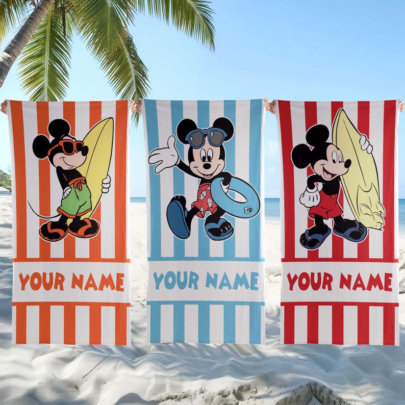 May include: Three rectangular beach towels featuring Mickey Mouse graphics. The left towel is orange-striped, the center is blue-striped, and the right is red-striped. Each towel displays the text YOUR NAME at the bottom in a bold font.