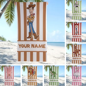 May include: A rectangular beach towel featuring a vertical striped pattern in white and brown. The centre displays a graphic of the character Woody from Toy Story, with a horizontal band below containing the placeholder text YOUR NAME.