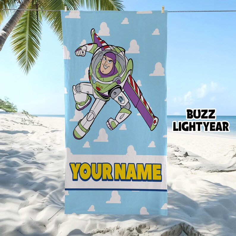 Puede incluir: Una toalla de playa rectangular con fondo azul claro y nubes blancas. En el centro muestra un gr&aacute;fico de Buzz Lightyear en posici&oacute;n de vuelo. Debajo del personaje, el texto YOUR NAME est&aacute; impreso en letras may&uacute;sculas amarillas.