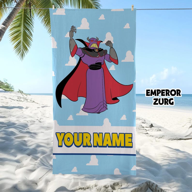 Op de afbeelding: Een rechthoekige strandhanddoek met een lichtblauwe achtergrond en witte wolken. Het personage Keizer Zurg staat in het midden afgebeeld, gekleed in een paars gewaad met een rode cape. Onder het figuur staat de tekst EMPEROR ZURG en YOUR NAME.