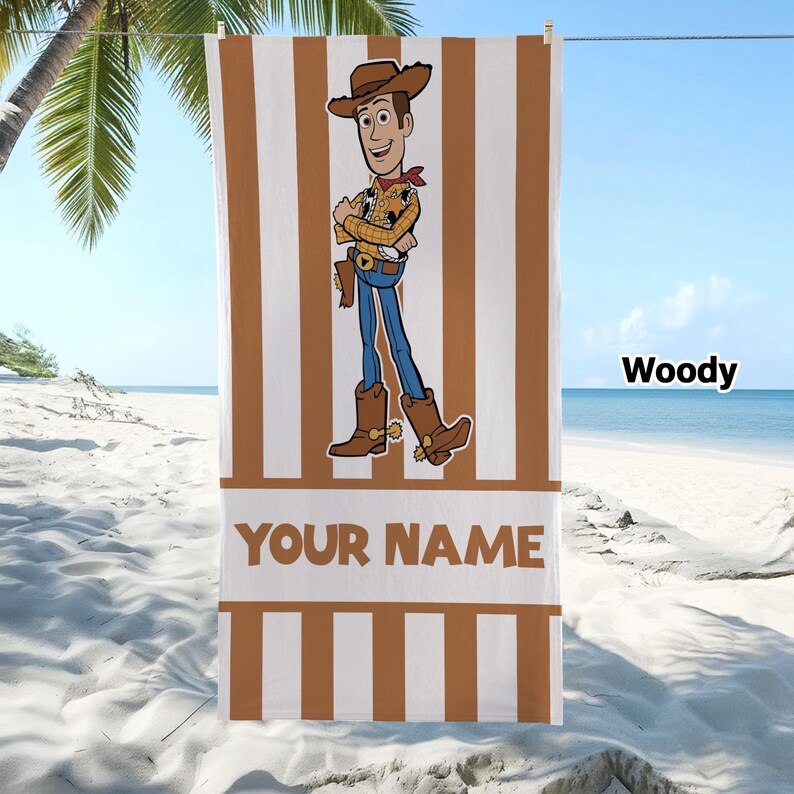 May include: A rectangular beach towel featuring a vertical brown and white striped pattern. The centre displays a cartoon character wearing a cowboy hat, yellow shirt, and blue jeans. The text "YOUR NAME" is printed in brown below the character.