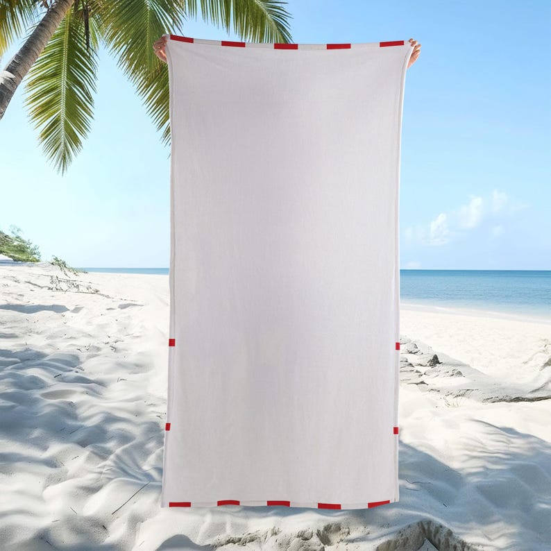 May include: A rectangular white beach towel featuring a thin red border with evenly spaced red rectangular accents along the top, bottom, and side edges. The towel is held vertically, displaying a clean, solid white center surface area.
