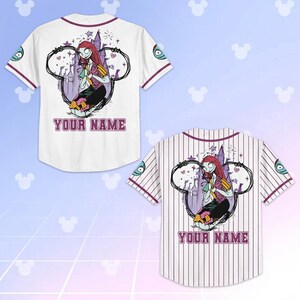 May include: Two baseball jerseys, one white and one striped, featuring a cartoon character design. The design includes a character with red hair, a purple castle, and the text "YOUR NAME" in a purple font. The jerseys have purple accents.