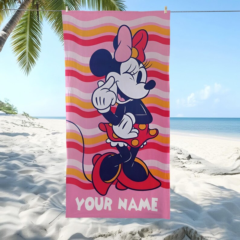 May include: A rectangular beach towel featuring a graphic of Minnie Mouse wearing a red polka-dot skirt and a pink bow. The background consists of horizontal wavy stripes in shades of pink, orange, and red. The text YOUR NAME is printed in white.