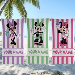 Pode incluir: Tr&ecirc;s toalhas de praia retangulares com gr&aacute;ficos da Minnie Mouse sobre fundos de listras verticais em roxo, verde e rosa. Cada toalha exibe o texto YOUR NAME na parte inferior, com a Minnie Mouse retratada em diferentes poses e roupas.
