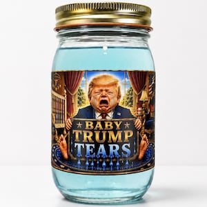Op de afbeelding: Een doorzichtige glazen pot met een goudkleurig metalen deksel, gevuld met een lichtblauwe vloeistof. Het etiket bevat een illustratie van een huilend persoon in een pak, met de tekst "BABY TRUMP TEARS" in grote, gouden en blauwe letters.