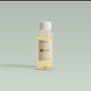 May include: A clear glass bottle with a white cap, containing a light amber liquid. The label reads "riossence No. 4" and "ocean" with a sunburst graphic. The bottle is 1.69 fl oz.