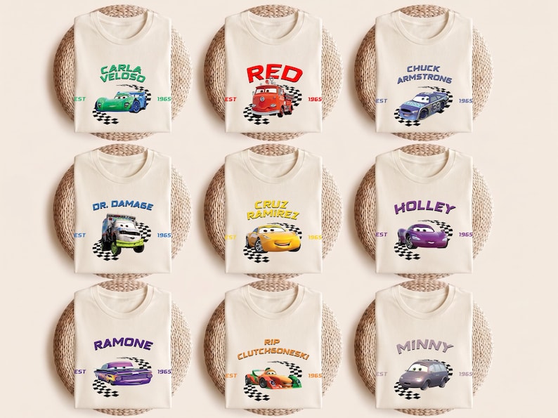 May include: Nine cream-colored t-shirts, each featuring a different character from the animated movie "Cars." The shirts display character names and car illustrations above a checkered flag design. The text "EST 1965" is also present on each shirt.