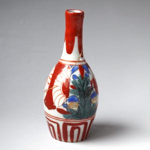 May include: A small ceramic bottle with a narrow neck, featuring a white base decorated with red, blue, and green floral and geometric patterns. The surface displays a visible gold-colored repair line running vertically along the side of the body.