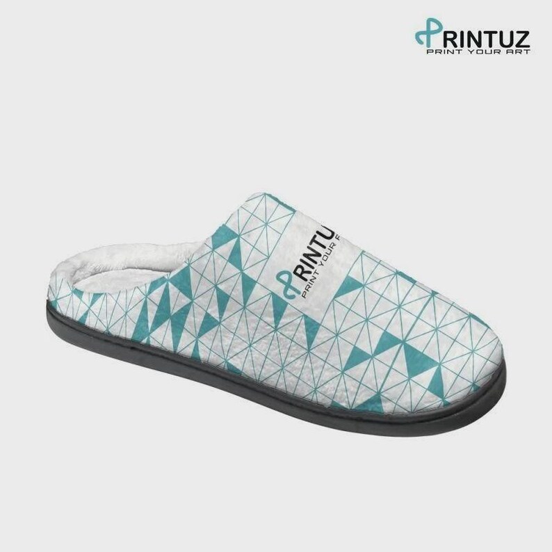 May include: A slip-on slipper featuring a white and teal geometric triangle pattern across the upper. The slipper has a dark gray sole and a white interior lining. The text PRINTUZ PRINT YOUR ART is printed in black and teal on the side.