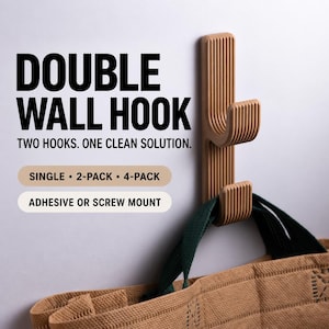 May include: A tan double wall hook with a vertical ribbed texture, featuring two hooks for hanging items. The text reads: DOUBLE WALL HOOK, TWO HOOKS. ONE CLEAN SOLUTION. SINGLE, 2-PACK, 4-PACK, ADHESIVE OR SCREW MOUNT. A brown bag hangs from the bottom hook.