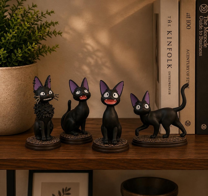 May include: Four black cat figurines with large pointed ears and purple inner ears, each on a circular base. One cat has textured fur, while the others are smooth. They display various expressions with open mouths, wide eyes, and long whiskers.