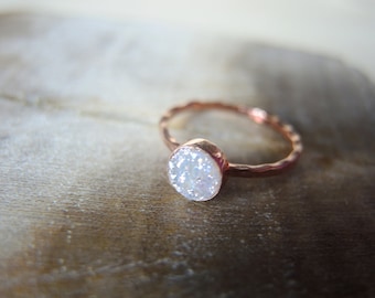 May include: A rose gold ring featuring a white opal stone. The ring has a hammered, textured finish.