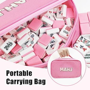 Pu&ograve; includere: Una borsa da trasporto in tessuto rosa con la scritta MAHJ stampata sul davanti, riempita con una collezione di tessere del mahjong bianche e rosa con vari simboli, caratteri e motivi neri e rossi, dotata di una maniglia per il trasporto.