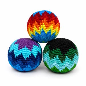 May include: Three colorful crocheted juggling balls. One ball features a vibrant rainbow pattern of red, orange, yellow, and blue. Another ball has a blue and purple design, and the third is black and green.