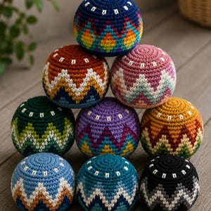 May include: A collection of nine colorful, crocheted balls arranged in a pyramid. Each ball features a unique combination of colors, including blue, orange, pink, green, purple, and yellow, with white zigzag patterns. The balls are likely juggling balls.