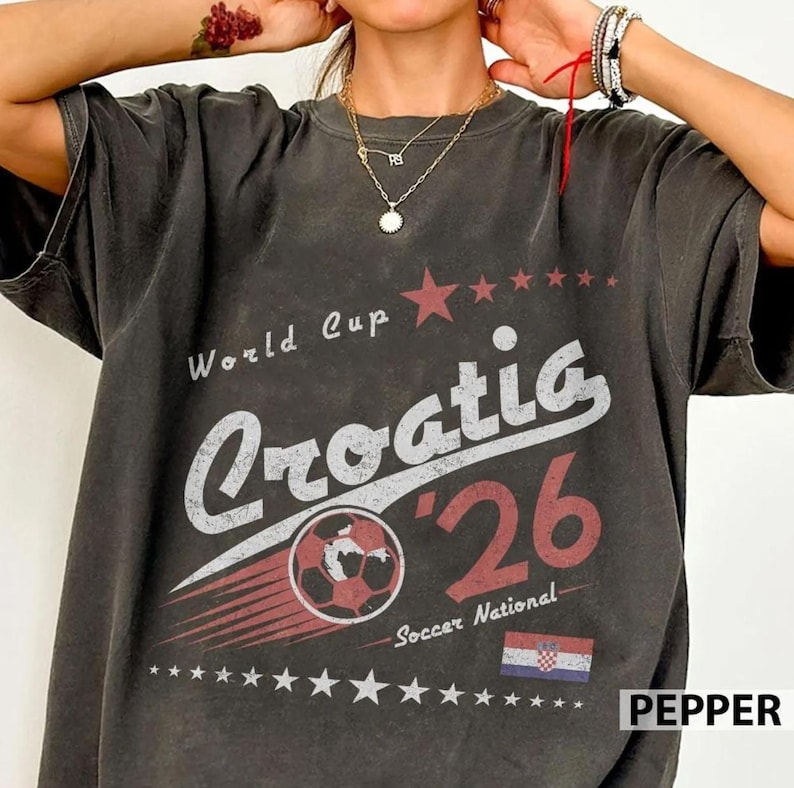 May include: A charcoal gray t-shirt featuring a distressed graphic print that reads World Cup Croatia '26 Soccer National. The design includes a soccer ball, a small Croatian flag, and rows of stars in red and white, creating a vintage aesthetic.