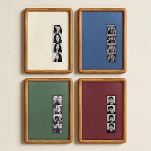 May include: Four rectangular wooden frames with light brown finish, each containing a vertical black and white photo strip. The frames feature solid-colored mats in cream, blue, green, and burgundy, surrounding the central photo strips.