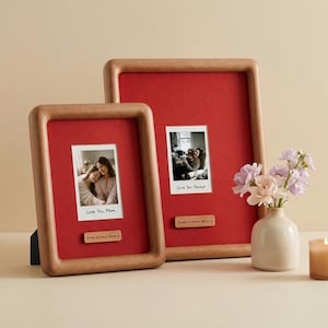 Op de afbeelding: Twee houten fotolijsten met rode achtergronden. Elke lijst bevat een kleine foto en een houten plaatje met de tekst "Love You, Mom" en "Home is where Mom is". Een kleine vaas met bloemen en een kaars staan naast de lijsten.