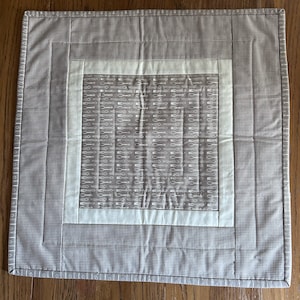 May include: A square gray and white quilted table runner with a smaller square in the center featuring a white pattern of spoons and forks on a gray background.