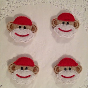 May include: Four felt monkey appliques with red hats. Each applique has a white face with embroidered black eyes and a red mouth.