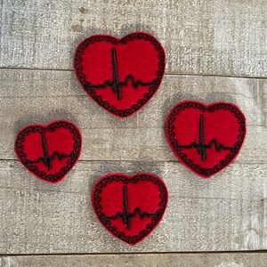 May include: Four red felt heart-shaped patches with black embroidered outlines and a black EKG line inside each heart.