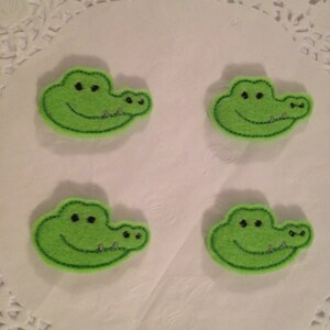 May include: Four green felt alligator head appliques with embroidered eyes and teeth.
